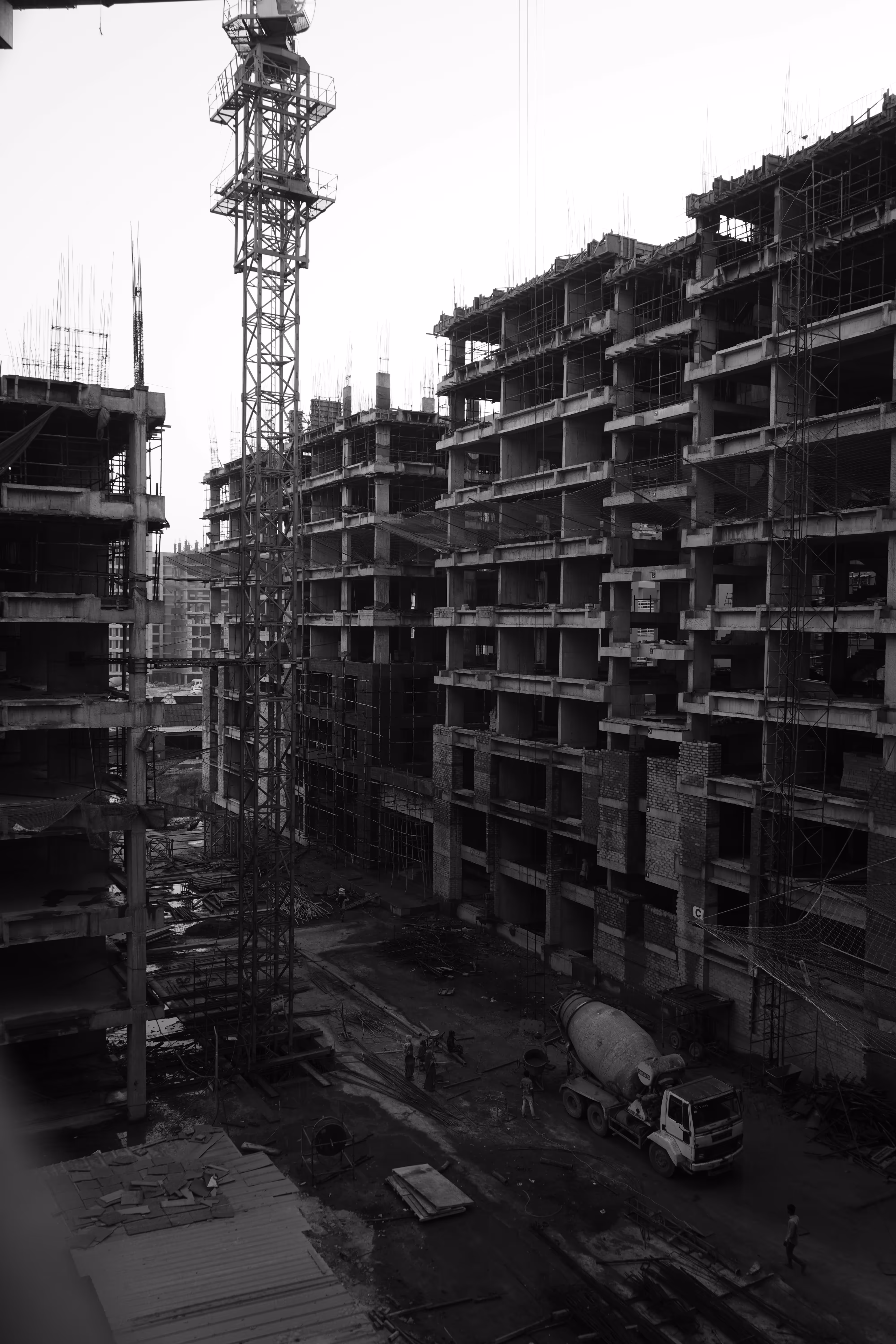 Ein Schwarz-Weiß-Bild einer großen Baustelle mit mehreren im Bau befindlichen Gebäuden und einem Kran im Vordergrund. Unten ist ein Betonmischer zu sehen. Das Bild symbolisiert, dass diese Webseite gerade noch gebaut wird.